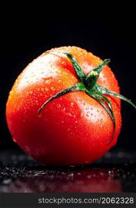 One ripe tomato on the table. On a black background. High quality photo. One ripe tomato on the table.