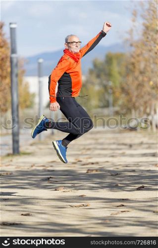 One senior runner man jumping arms up after running