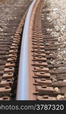 One single train track in gravel with a curve.