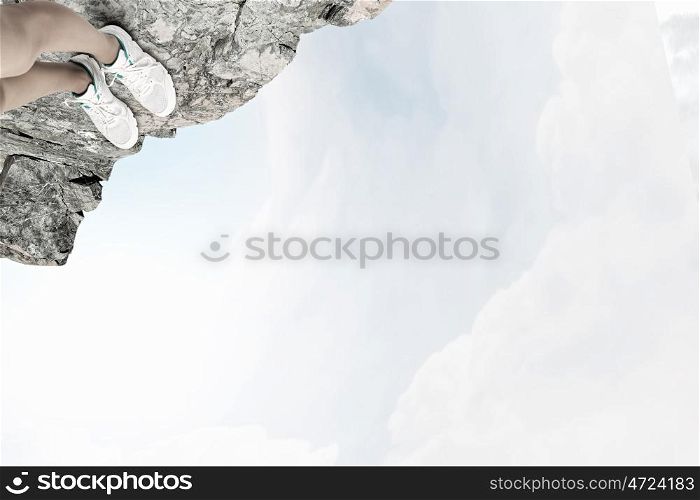 One step to gap. Close up of woman legs standing on the edge of rock