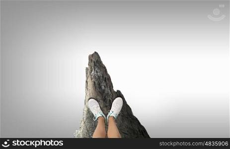 One step to gap. Close up of woman legs standing on the edge of rock