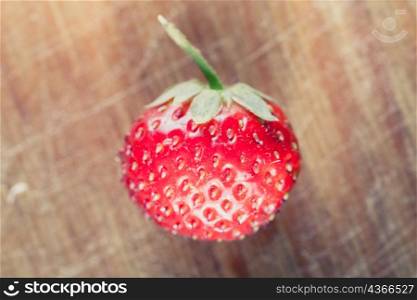 one strawberry on the wooden plank