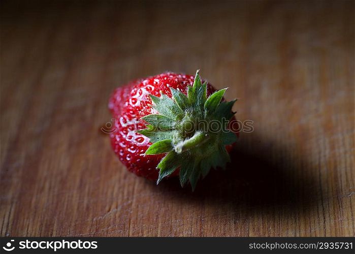 one strawberry on the wooden plank, back view