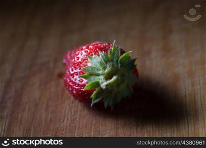 one strawberry on the wooden plank, back view