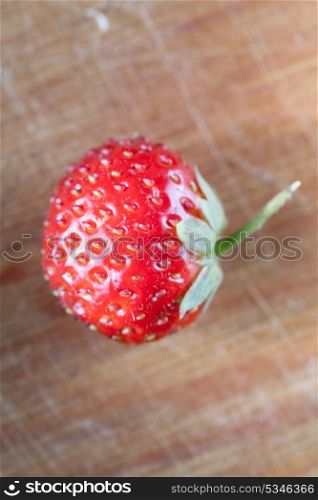 one strawberry on the wooden plank, macro or very closeup shot