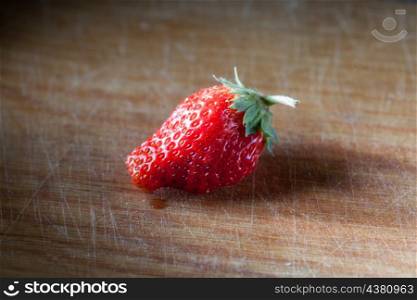 one strawberry on the wooden plank, side view