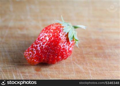 one strawberry on the wooden plank, side view