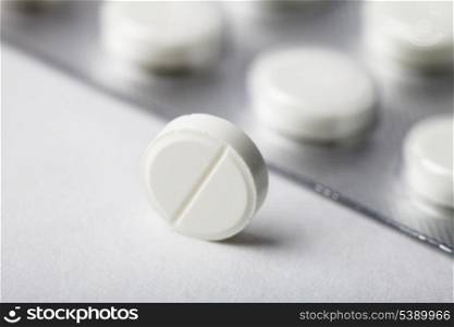 One tablet closeup on background with pack of pill