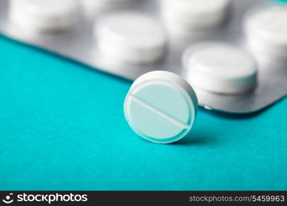 One tablet closeup on background with pack of pill