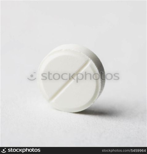 One tablet closeup on background with pack of pill