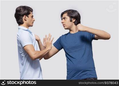 One teenage boy pulling the other by the collar of his shirt against white background