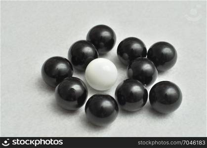 One white and a lot of black balls displayed on a white background