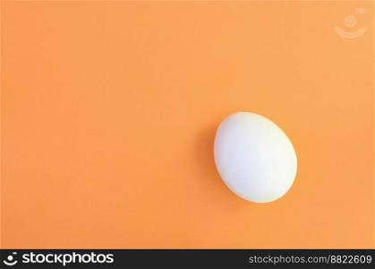 One white easter egg on a bright orange background