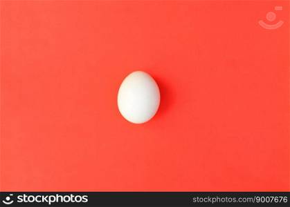 One white egg on a bright red background