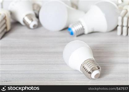 one white LED bulb light close up and energy-saving lamps on gray wooden board