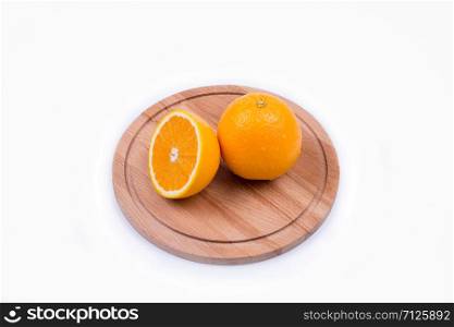 one whole and half an orange lie on a round wooden board, top view. chopped orange on a wooden board