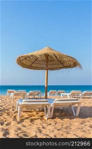 One wicker beach parasol with beach beds at blue sea