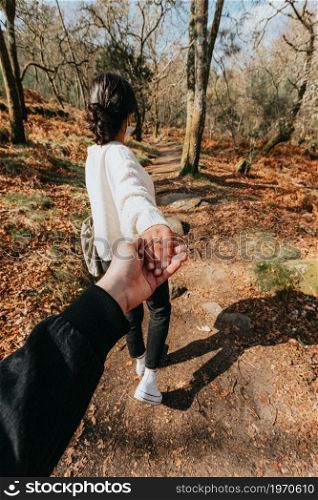 One woman in the middle of the forest holding the hand of the photographer using a rubber ring while walking