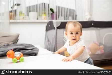 One year old baby portrait holding to coffe table in bright room. Baby background. One year old baby portrait holding to coffe table in bright room