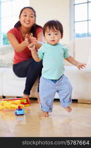 One Year Old Boy Taking First Steps With Mother