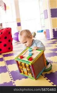 One year&rsquo;s old toddler boy plays with fine motor skills cube at the playroom