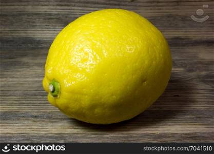 One yellow lemon on wooden background.