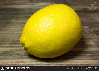 One yellow lemon on wooden background.