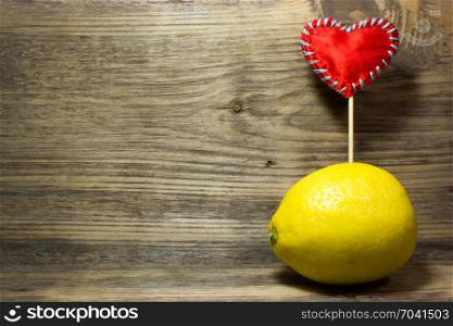 One yellow lemon on wooden background. Free space for text.