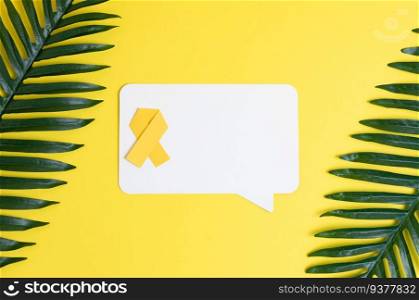 One yellow origami paper ribbon with blank white callouts with space for text and palm branches around the edges lies on a yellow background, flat lay close-up. Concept for World Childhood Cancer Day.. Yellow ribbon, empty kalyut and palm branches on yellow.