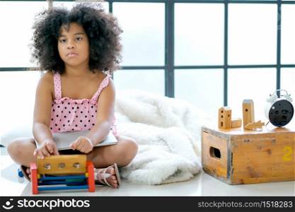 One young African girl look boring with playing some toys and sit on the floor in room with day light.