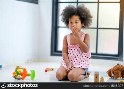 One young African girl sit and express of frighten or shock during plays some toys in the living room.