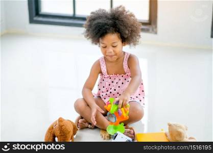 One young African little girls play toys and look fun and enjoy in living room with day light.