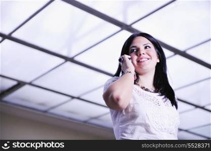 one young happy business woman talking by cellphone indoor in bright building