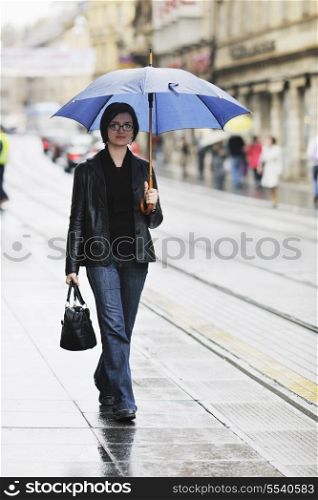 one young happy woman walking in cyti with rainy weater and blue umbrella