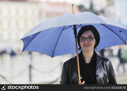 one young happy woman walking in cyti with rainy weater and blue umbrella