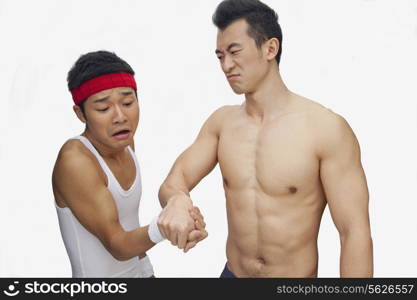 One young man beating another at arm wrestling, studio shot