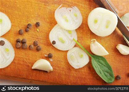 Onion, garlic, bay leaves and black pepper. Spicery on cutting board