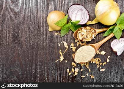 Onion powder and dried flakes in two spoons, purple and yellow onions, fresh basil on dark wooden board background from above