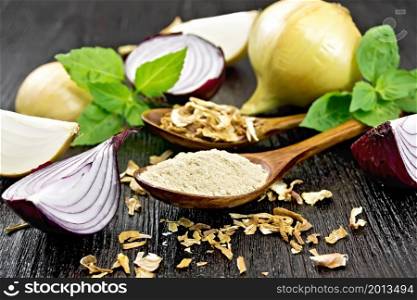 Onion powder and dried flakes in two spoons, purple and yellow onions, fresh basil on dark wooden board background
