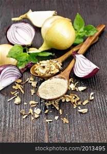 Onion powder and dried flakes in two spoons, purple and yellow onions, basil on wooden board background