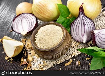 Onion powder in a bowl on sacking, purple and yellow onions, dried onion flakes and basil on wooden board background