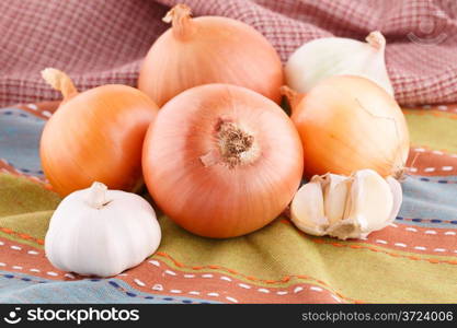 Onions and garlics on colorful towel.