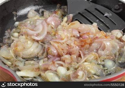 Onions being caramelised in a frying pan