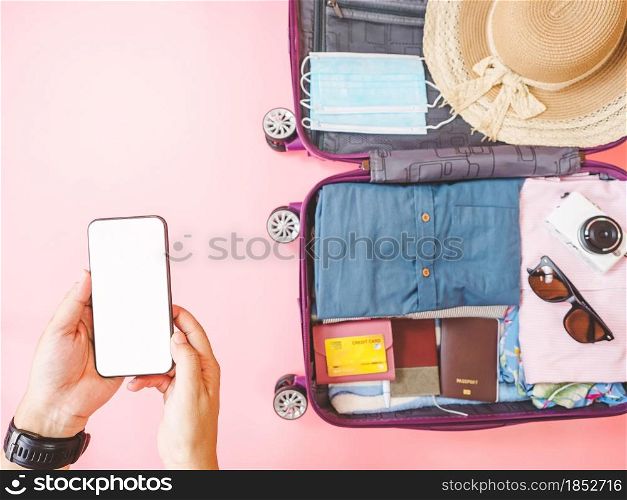 online booking travel and pay concept from smartphone and suitcase with summer collection on pink background.