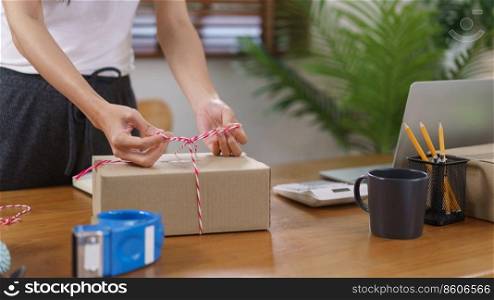 Online business concept, Asian business women packing product into parcel box and tying with rope.