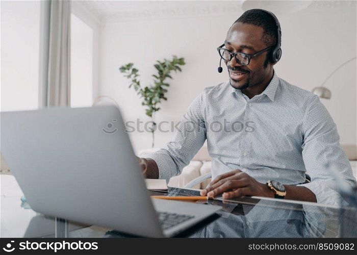 Online business talk. Afro american guy is speaking in front of camera. Happy businessman in formal wear and headset has online meeting in zoom. Manager of client support service has conversation.. Manager of client support service has conversation. Afro american guy speaking in front of camera.