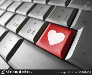 Online love and valentines lovers concept with a heart icon and symbol on a red computer key.