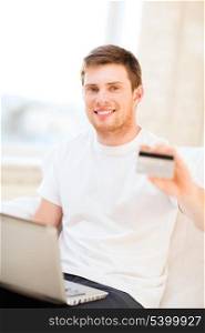 online or internet shopping concept - smiling man with laptop and credit card at home