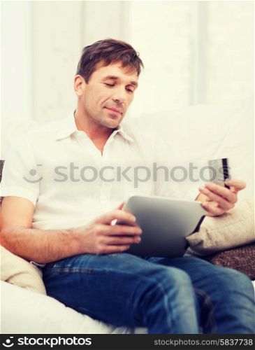 online or internet shopping concept - smiling man with tablet pc and credit card at home