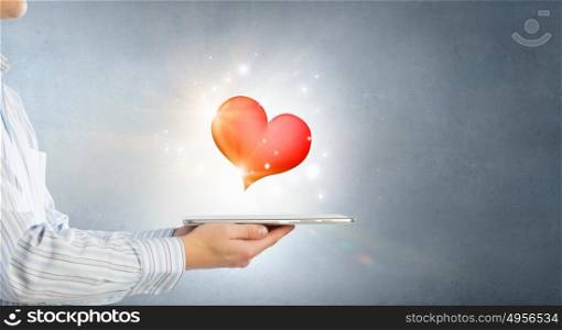 Online romantic chat. Male hand holding tablet pc with red heart on screen